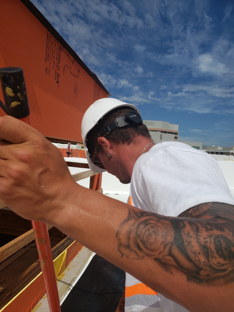 Seamcraft crew member installing self-adhered membrane on a commercial rooftop